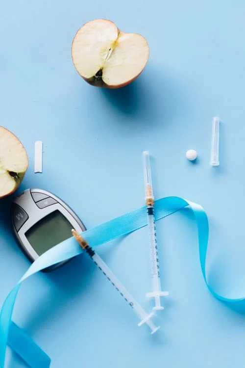 Blood sugar meter and insulin syringe on a blue background for diabetes care