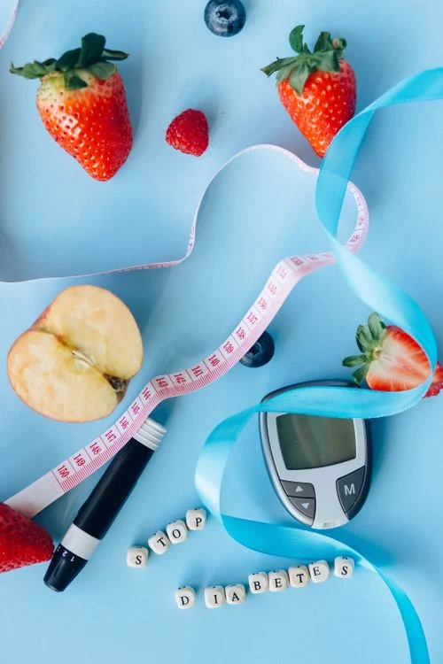 Fresh fruits, glucose meter and diabetes awareness ribbon on a blue background