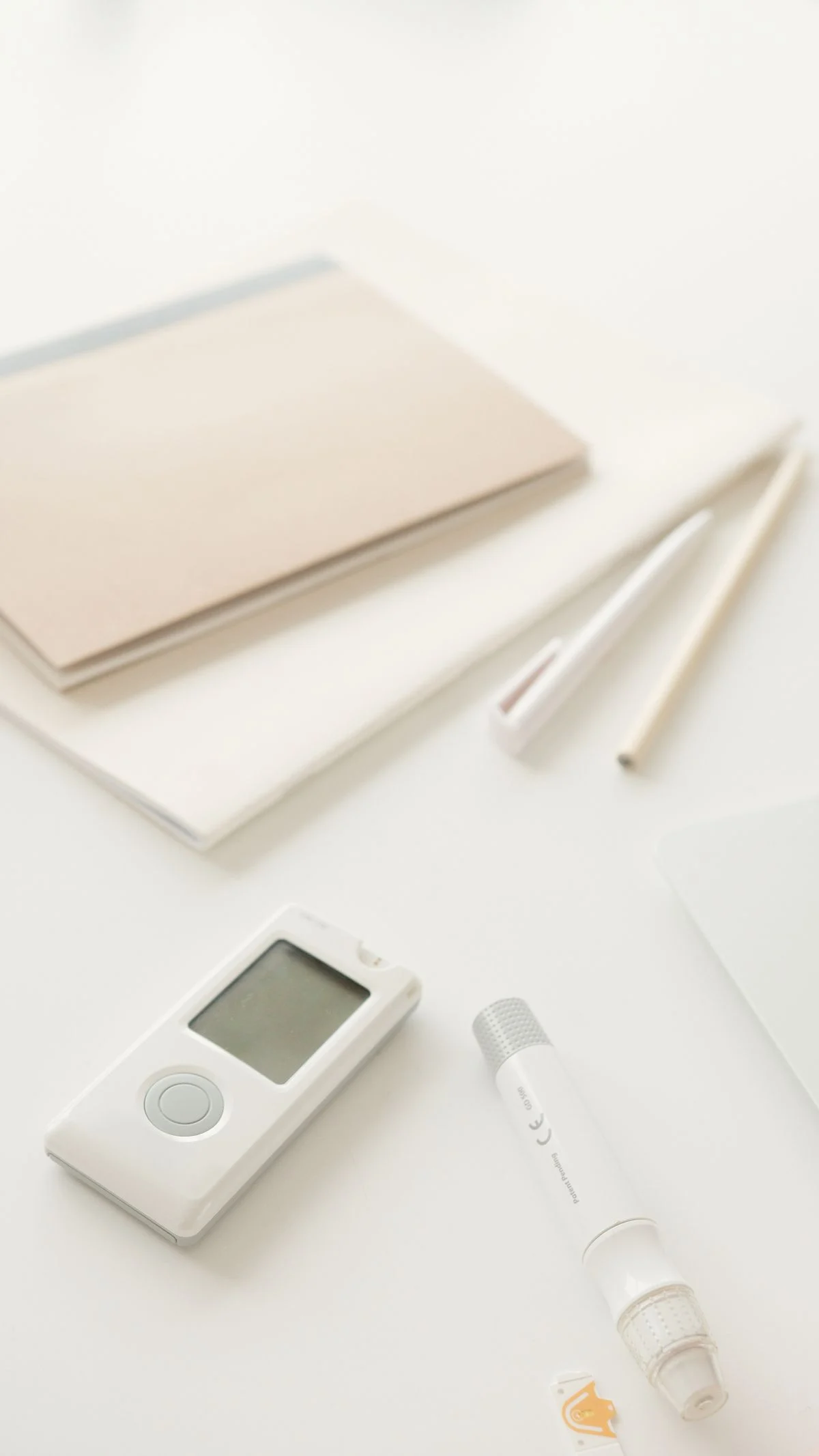 Glucometer and lancet pen on a white surface for blood glucose testing