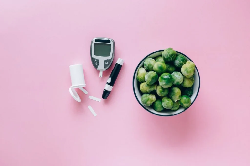 Glucometer placed next to fresh brussels sprouts for blood sugar management
