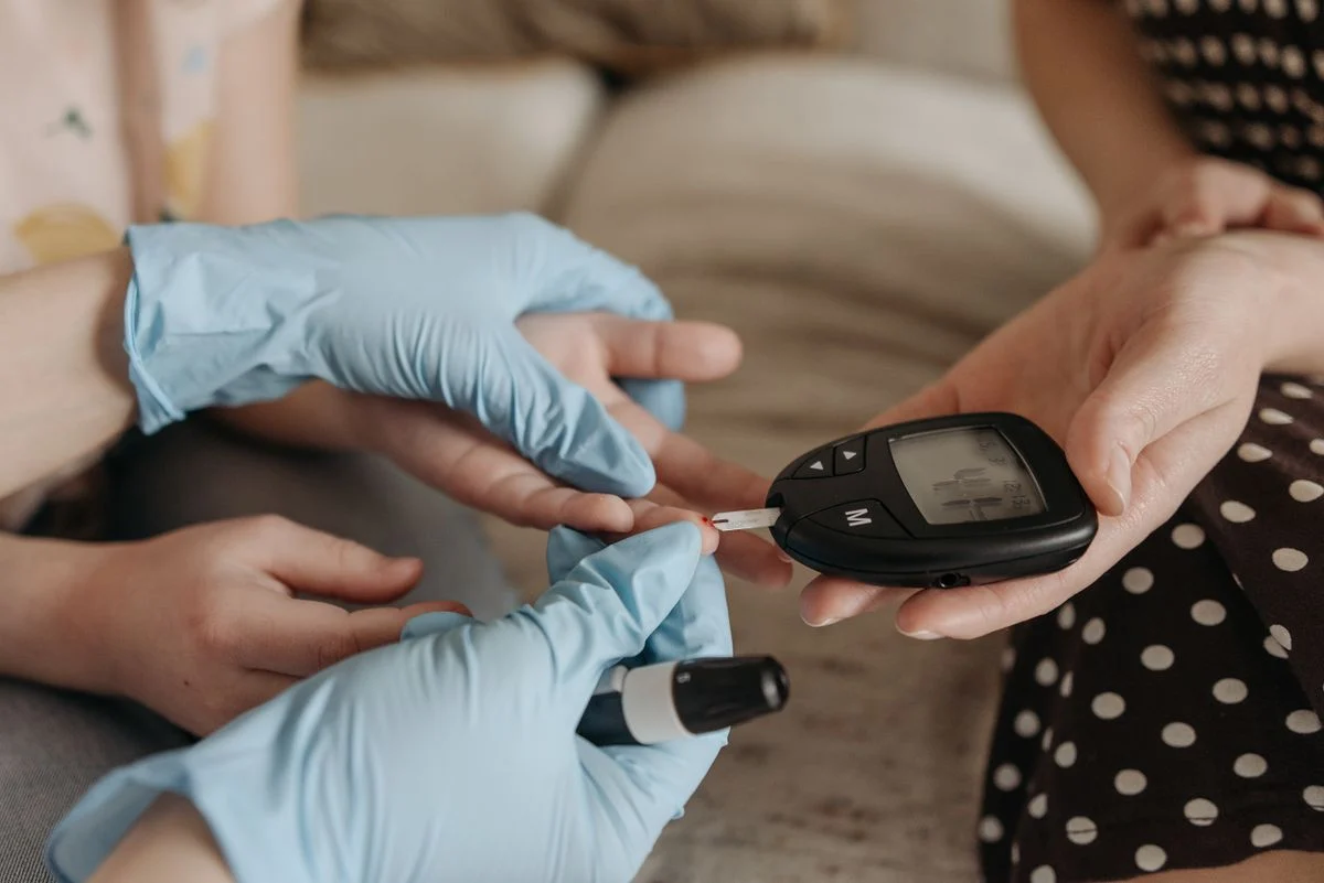 Hands holding a blood glucose meter showing prediabetes range reading