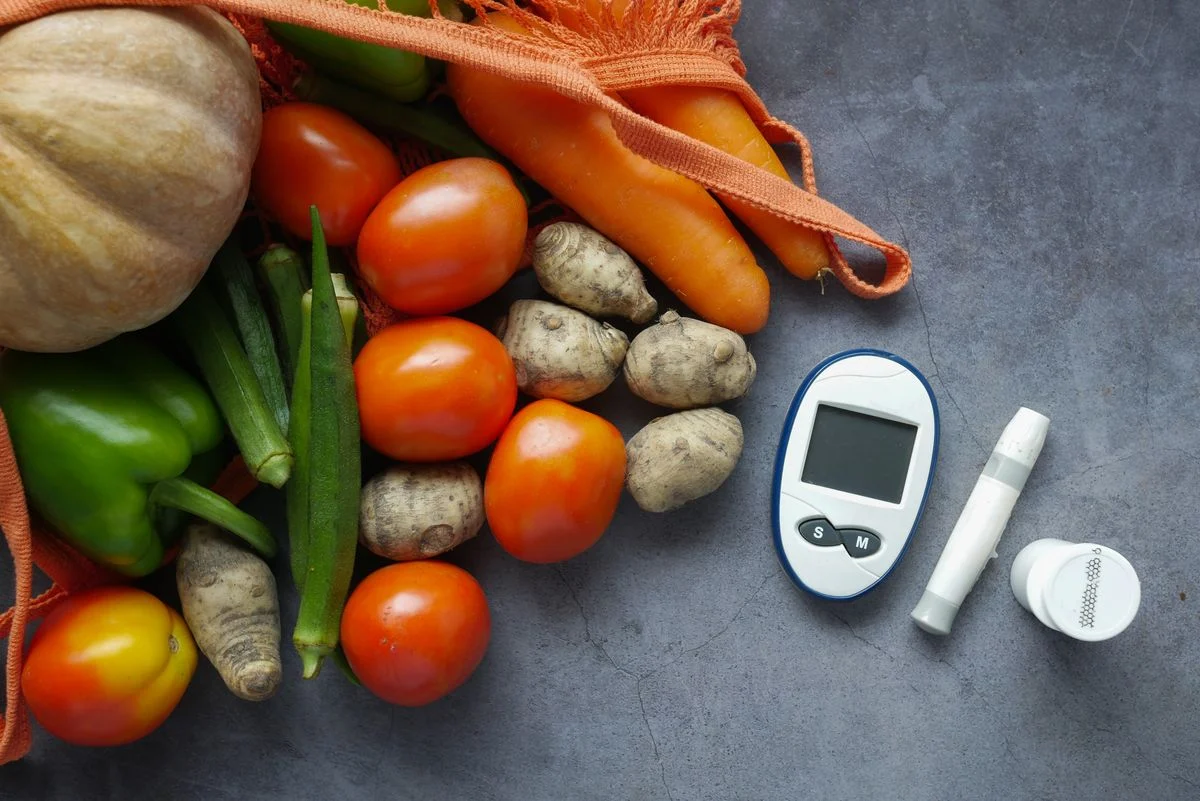 Vegetables and diabetes monitoring equipment on a table, illustrating the link between food choices and blood sugar