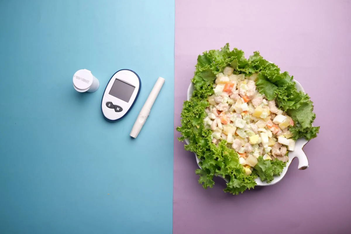 A fresh salad with leafy greens and colourful vegetables beside diabetes monitoring equipment