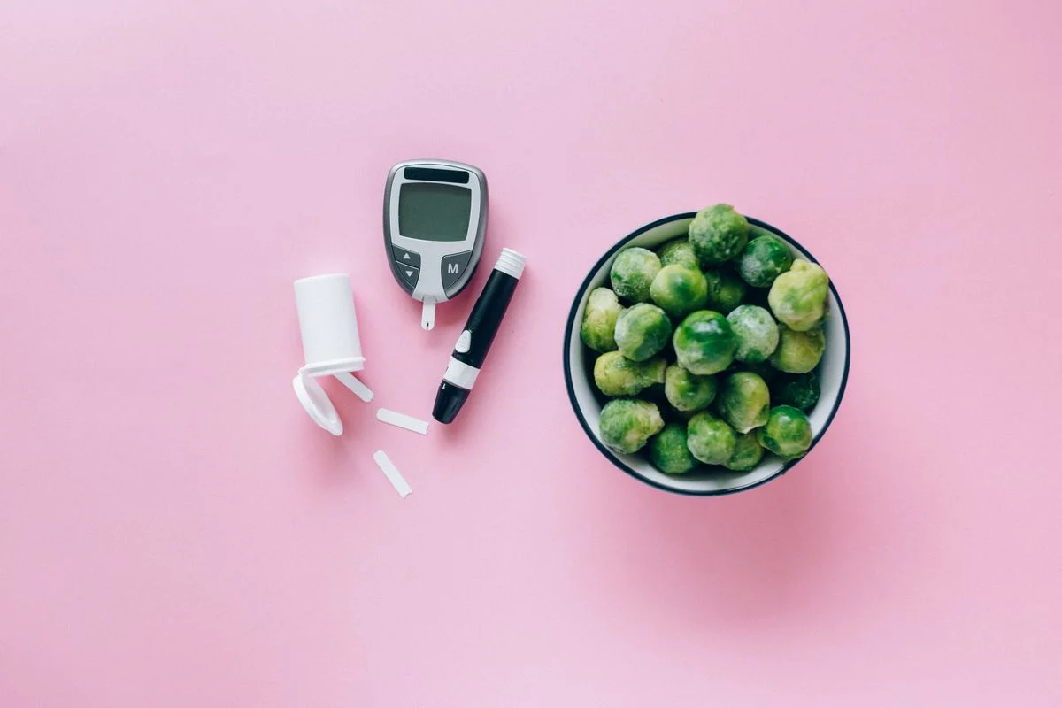 A glucometer beside a bowl of fresh Brussels sprouts representing blood sugar management through food choices
