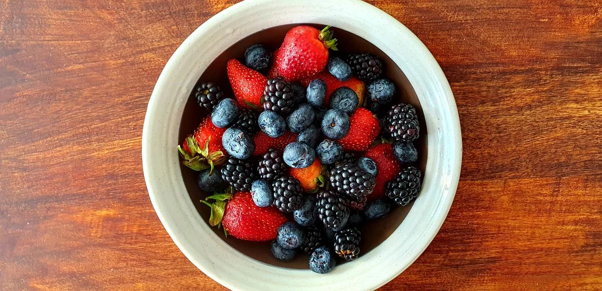 A white ceramic bowl filled with mixed berries — blueberries, raspberries and strawberries — low-GI fruits ideal for diabetes