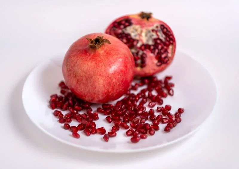 Freshly cut pomegranate showing ruby-red arils on a plate – whole fruit is better than juice for diabetes