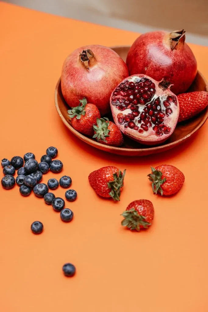 Fresh fruits in a wooden bowl including pomegranate – pomegranate's polyphenols support cardiovascular health in diabetes