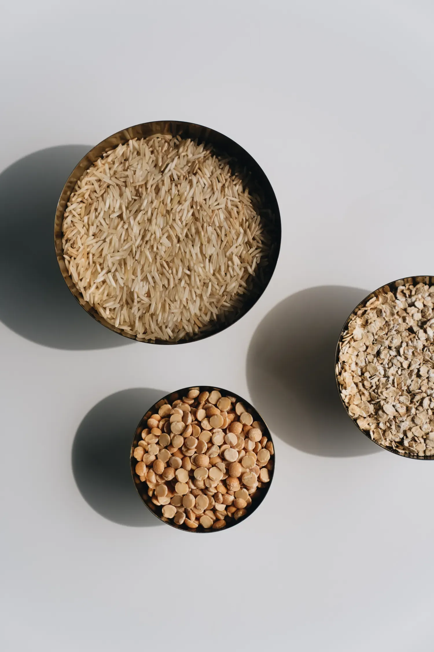 Bowls of uncooked rice, lentils and oats.