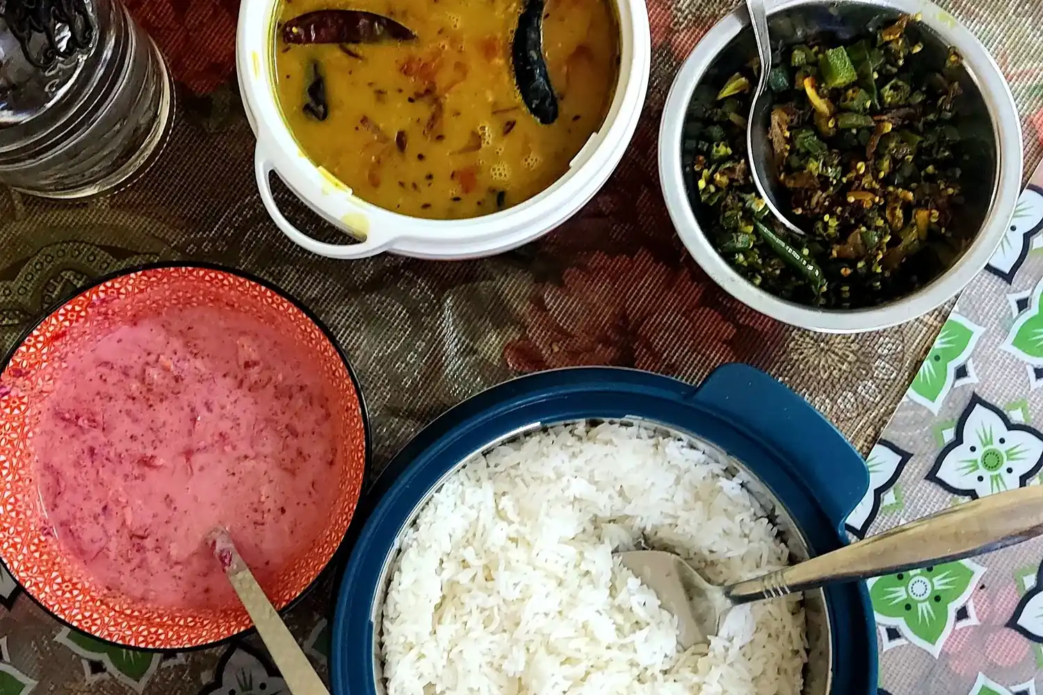 Shared serving dishes containing rice, dal and vegetables.
