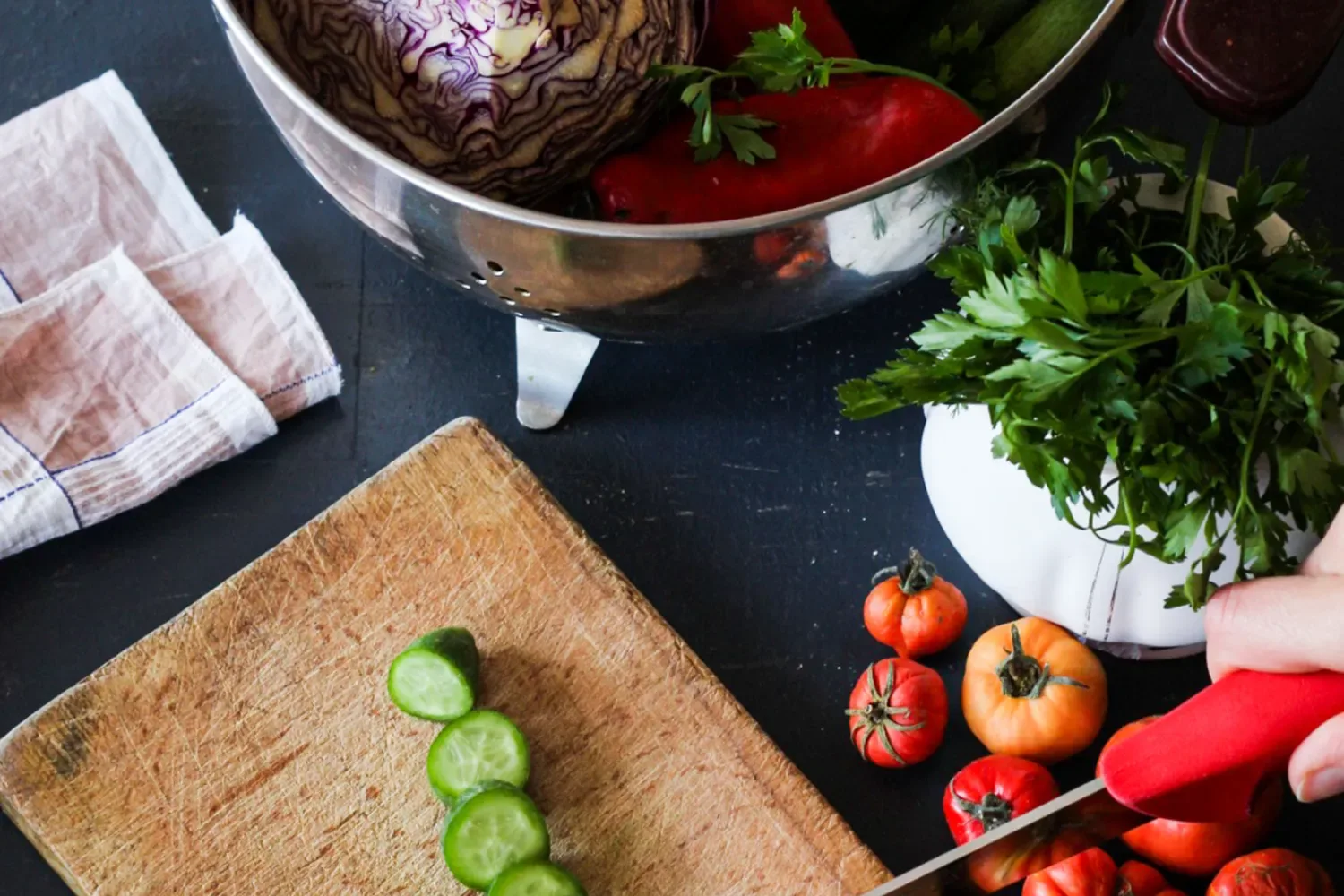 Cucumber slices, tomatoes, cabbage and other vegetables during meal preparation.