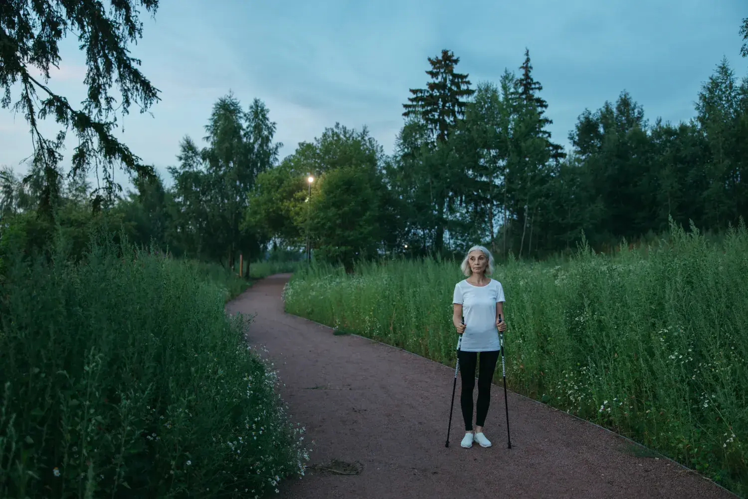 Woman outdoors on a path with walking poles.