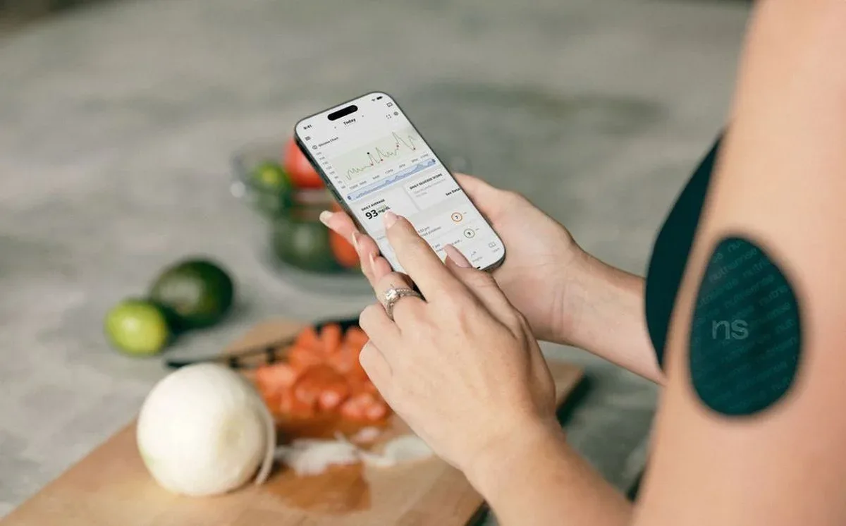 Woman using smartphone app to measure blood sugar level with CGM sensor — Twin Health program lifestyle tracking